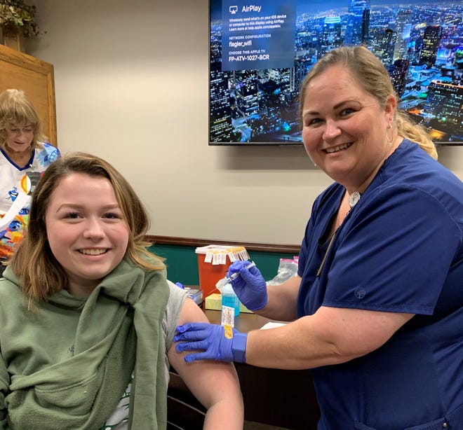 Registered nurse Shanna Brayman gives a flu shot to her daughter Faith Buckley, a junior at Flagler Palm Coast High School. [Photo provided]