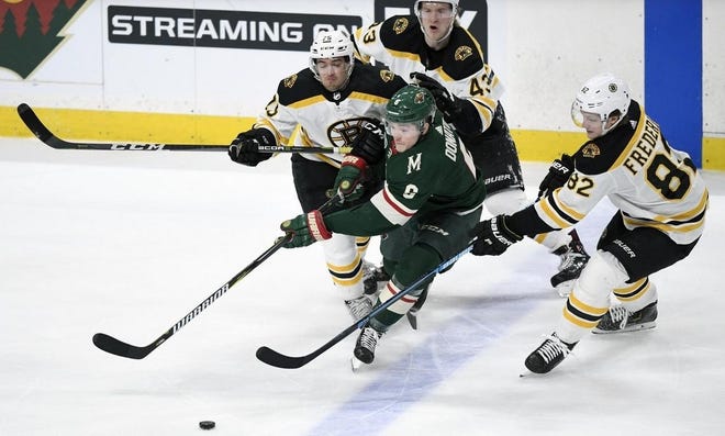 Minnesota Wild forward Ryan Donato (6) passes away from Boston Bruins Connor Clifton (75), Danton Heinen (43) and Trent Frederic (82) during the third period of an April game in St. Paul, Minn. [AP File Photo/Hannah Foslien]