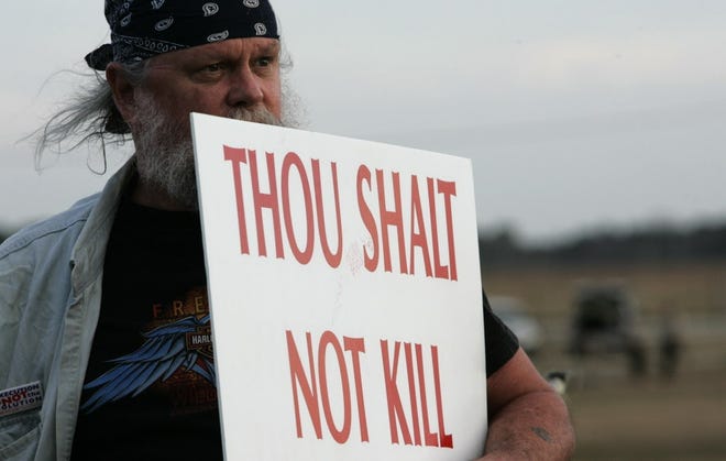 Tom Stanis, of Daytona Beach looks across State Road 16 towards the Florida State Prison as he holds a sign, standing in opposition to the death penalty and to the execution of Wayne Tompkins, in Starke, Fl, Wednesday, February 11, 2009. [David Massey/Gannett File]