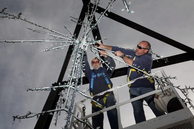 City of Burlington worker Mark Runnells and Burlington Riverfront Entertainment board member Matt McChesney, install one of two giant lighted ten foot snowflake decorations made by Flint Cliff Manufacturing Monday on the Port of Burlington speaker bays. BRE will also be hosting a tree lighting ceremony and entertainment Saturday in the Memorial Auditorium parking lot immediately after the 5 p.m. Lighted Holiday Parade on Jefferson Street. [John Lovretta/thehawkeye.com]