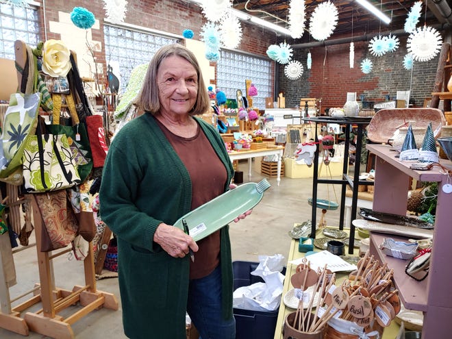 Artisan Nancy Webb holds a caprese salad bowl she made, one of a variety of items she has for sale at Local Roots in Wooster. Behind her are multiple items, all worthy gifts, made by other area craftspeople. Webb herself works with multiple forms of artistic media.