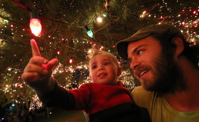 Hundreds of people turned out for the 61st annual Christmas Town U.S.A. Tree Lighting Ceremony in downtown McAdenville Thursday night. Here, Ryder Orris (18 months) and his father Justin Orris check out the lights moments after they were turned on. [Mike Hensdill/The Gaston Gazette]