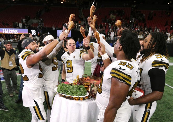 New Orleans Saints players celebate a 26-18 victory over Atlanta with turkey legs on Thanksgiving Day while clinching the NFC South. [ CURTIS COMPTON/ATLANTA JOURNAL CONSTITUTION ]