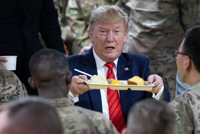 President Donald Trump holds up a tray of Thanksgiving dinner during a surprise Thanksgiving Day visit to the troops, Thursday, Nov. 28, 2019, at Bagram Air Field, Afghanistan. (AP Photo/Alex Brandon)