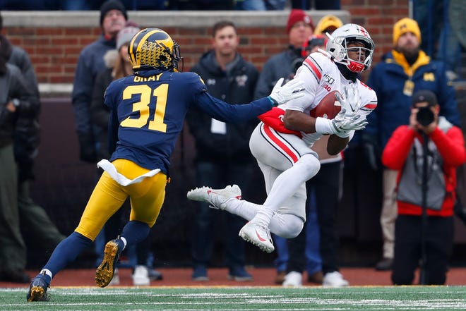 Ohio State wide receiver Garrett Wilson (5) catches a 47-yard pass as Michigan defensive back Vincent Gray (31) defends in the first half Saturday in Ann Arbor, Mich. [PAUL SANCYA/THE ASSOCIATED PRESS]