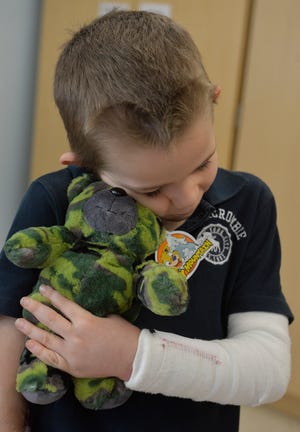 Elijah Andrews, 7, gives his camo teddy bear a hug at the Willet Children’s Hospital at Memorial Health University Medical Center. The Mercer University School of Medicine students and staff handed out 98 new and used teddy bears Monday to children at the hospital. The mascot for Mercer University is a bear. [Steve Bisson/savannahnow.com]