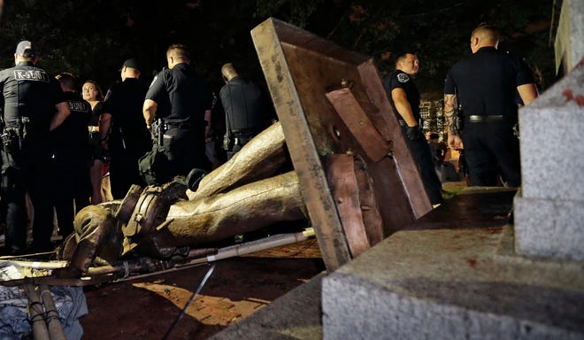 Police stand guard after the Confederate statue known as Silent Sam was toppled by protesters on campus at the University of North Carolina in Chapel Hill, N.C., Monday, Aug. 20, 2018. [AP Photo/Gerry Broome]