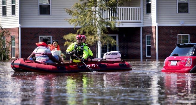 New York Urban Search and Rescue team members evacuate residents as floodwaters inundate the Heritage at Fort Bragg Apartments in Spring Lake on Sept. 18, 2018, in the aftermath of Hurricane Florence. [Julia Wall/The News & Observer via AP]