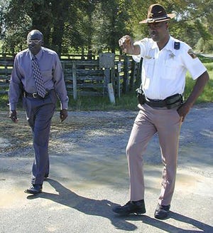 In this March 21, 2000 photo, Lowndes County Sheriff Willie Vaughner, left, and chief deputy John Williams stand at the intersection where Williams apprehended Jamil Abdullah Al-Amin on Monday evening in White Hall, Ala. Williams was fatally shot in the line of duty Saturday evening, Nov. 23, 2019, in a county near the state capital city, Alabama Gov. Kay Ivey said. Ivey tweeted that Lowndes County Sheriff Williams was þÄúa pillar of the community.þÄù (Al Benn/Montgomery Advertiser via AP)