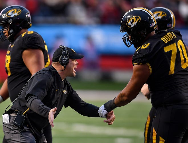 Missouri head football coach Barry Odom, left, congratulates offensive tackle Yasir Durant (70) after a touchdown against Arkansas during Friday's game at War Memorial Stadium in Little Rock. [Jimmy Jones/Special to the Tribune]