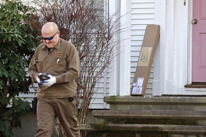 In this Nov. 26, 2019, photo a UPS man delivers a package to a residence in North Andover, Mass. Many out-of-state websites that facilitate online sales in Michigan would have to collect and remit the state's 6% sales tax under bills that won final legislative approval Wednesday and that could generate an additional $80 million to $120 million in revenue per year. (AP Photo/Elise Amendola)