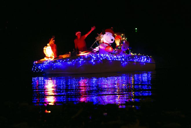 People wave from their Snoopy-themed boat during the Leesburg Christmas on the Water boat parade at Light Up Ski Beach in Leesburg. [Cindy Sharp/Correspondent]