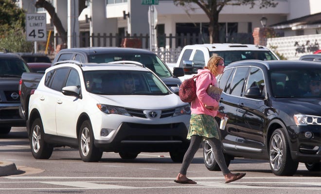 A pedestrian crosses Granada Boulevard at Nova Road on Monday as traffic waits at the light. Several pedestrian deaths have city leaders asking about strategies to make the roads safer. [News-Journal/David Tucker]