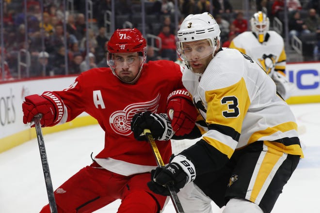 Detroit Red Wings center Dylan Larkin (71) and Pittsburgh Penguins defenseman Jack Johnson (3) battle for position in the second period of an NHL hockey game Saturday, Dec. 7, 2019, in Detroit. (AP Photo/Paul Sancya)