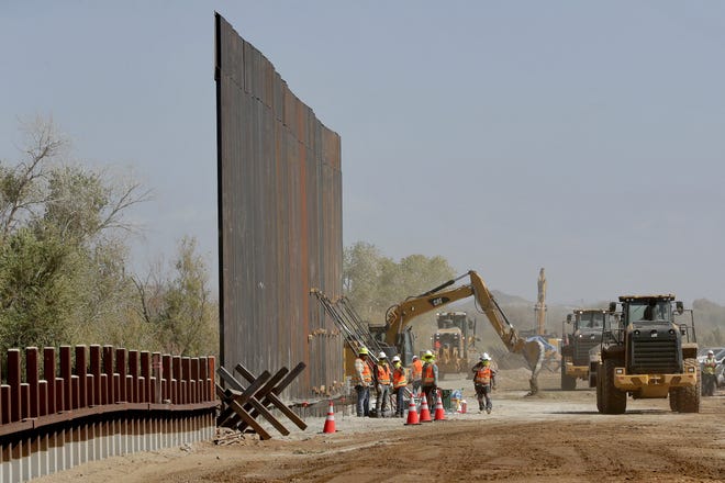 Government contractors erect a section of Pentagon-funded border wall on Sept. 10 along the Colorado River in Yuma, Ariz. Construction began as federal officials revealed a list of Defense Department projects to be cut to pay for President Donald Trump's wall. [AP / Matt York]