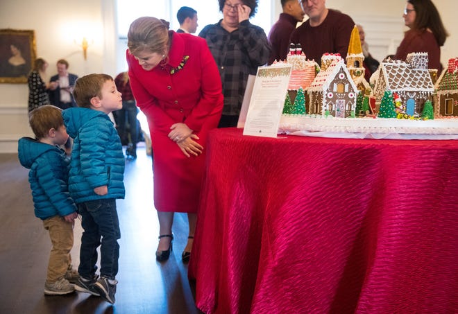 Ryan Elliott stands on tiptoe to get a better look at the gingerbread houses on display as his brother Andrew visits with first lady M.K. Pritzker at a holiday tour of the Governor's Mansion Saturday, Dec. 7, 2019. [Ted Schurter/The State Journal-Register]