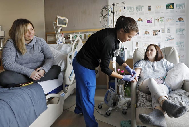 Destiny Mikes, 16, gets her arm checked by a nurse (declined giving name) while her mom Beth Mikes looks on at Children's Hospital December 4, 2019 after having her left arm amputated after a car crash. Destiny last week was on her way to put flowers at a roadside memorial for two of her classmates in Logan County who were killed in a car crash. And as she neared the crash site on the narrow, hilly country road, she too swerved on a a hill, and crashed. [Eric Albrecht/Dispatch]