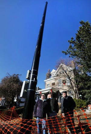 Residents of Bryden Road on the Near East Side found this 5G cell tower installed between the curb and sidewalk recently. At the pole are, from left, Sandy Mohr, Dale Abrams and Charles Abbot. Abbot, whose house is in the background, said of the pole’s installation: “Total surprise. Absolutely total surprise.” [Fred Squillante/Dispatch]