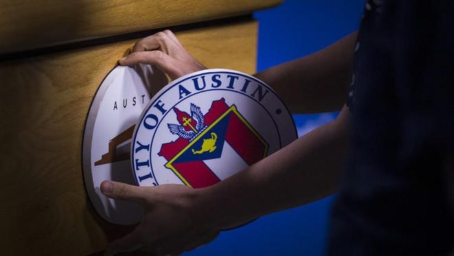A city of Austin employee switches out the podium seal before a news conference at City Hall. [Nick Wagner/American-Statesman]
