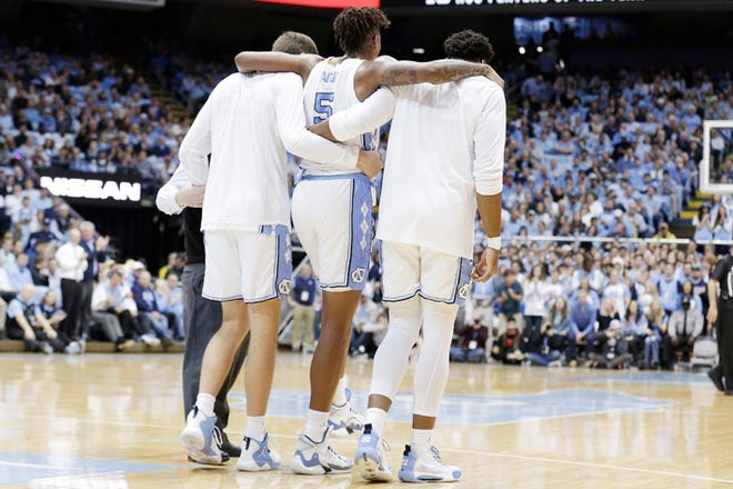 North Carolina teammates help Armando Bacot off the court during a game against Ohio State.