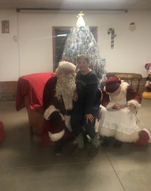 Emmi Enold takes a minute to visit with Santa at the Dellroy Christmas party on Saturday. (Times-Reporter / Jacquie Humphrey)