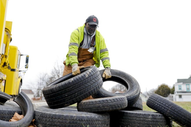 George Banks, a refuse collector with the city of Columbus, picks up tires that were illegally dumped last week on Parkwood Avenue on the East Side. Banks picked up 25 tires at that location, and a total of 64 from throughout the city. [Joshua A. Bickel/Dispatch]
