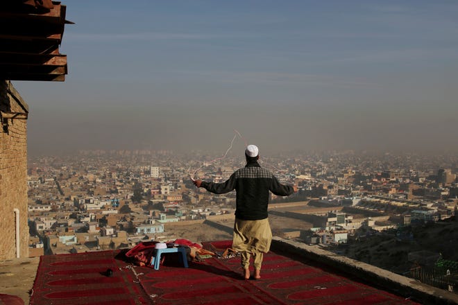 An Afghan boy skips on the rooftop of an Islamic seminary overlooking Kabul skyline enveloped in smog in Kabul, Afghanistan, Sunday, Dec. 8, 2019. (AP Photo/Altaf Qadri)