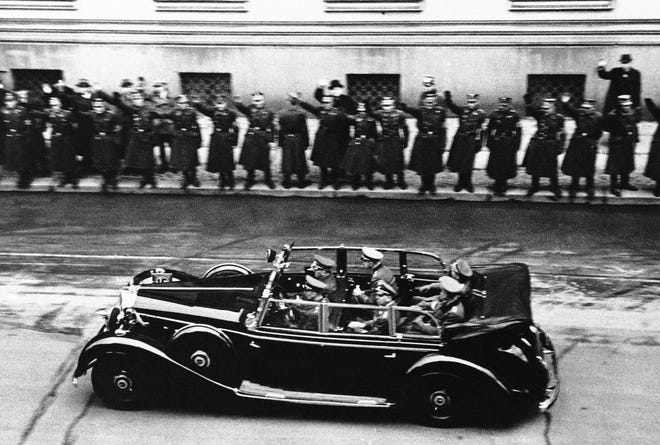 Adolf Herr Hitler, riding beside the driver, goes to the Reichstag in Berlin to tell the German people that papers have been handed the American representative on Dec. 11, 1941. Hitler passes in front of the Foreign Office inside which U.S. Charge D'Affaires Leland B. Morris is receiving formal papers of the German government’s declaration of war. The United States responded by declaring war on Germany. [THE ASSOCIATED PRESS]