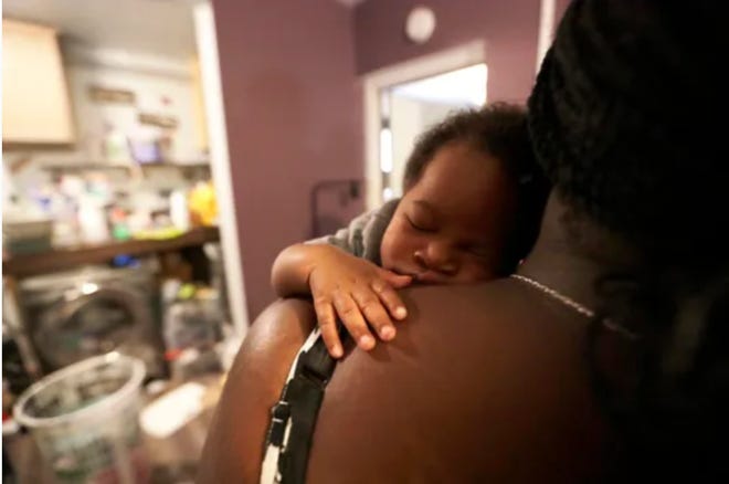 Milo, also known as the "community baby," sleeps on Talethia Edwards' shoulder. [Photo: Alicia Devine/Tallahassee Democrat]