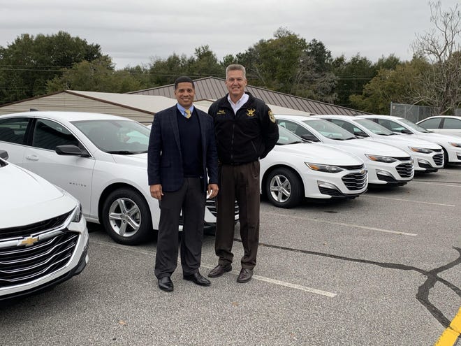 Superintendent Marcus Chambers (left) and Sheriff Larry Ashley (right) pose Thursday for a photo next to the new vehicles. [CONTRIBUTED PHOTO]
