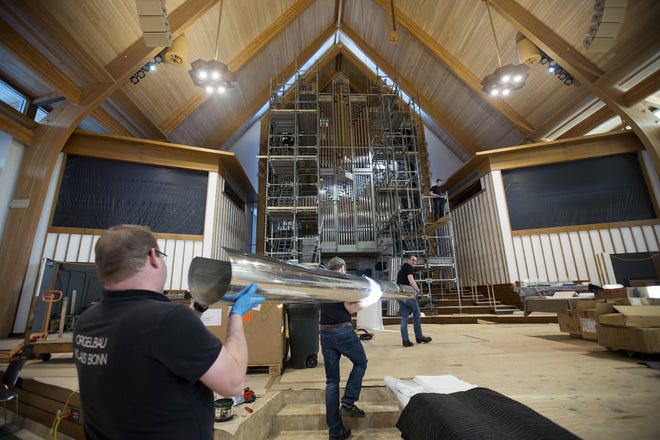 Moving a 200-pound, 16-foot-long pipe at First Community Church’s North Campus are, from left, Marc Jackson, Dominik Haubrichs and Horst Hoffmann, organ builders with Germany’s Orgelbau Klais. [Courtney Hergesheimer/Dispatch]
