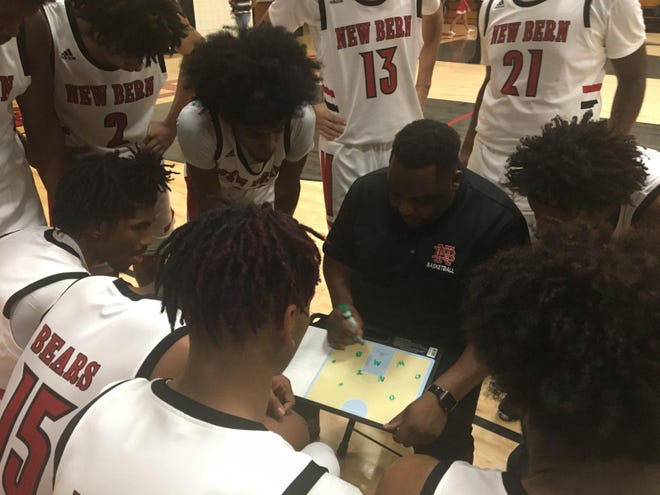 New Bern head coach Calvin Campbell (center with board) instructs his players before taking the court after a timeout in Friday night’s basketball game versus Jacksonville. The Bears fell to the Cardinals 59-45. [JORDAN HONEYCUTT / SUN JOURNAL STAFF]