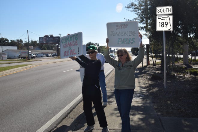 Anita Kurz (left) and Cay Burton hold signs at Oakmonte Plaza on Saturday to spread awareness for a state land conservation fund. [ERIN FRANCZAK/DAILY NEWS]