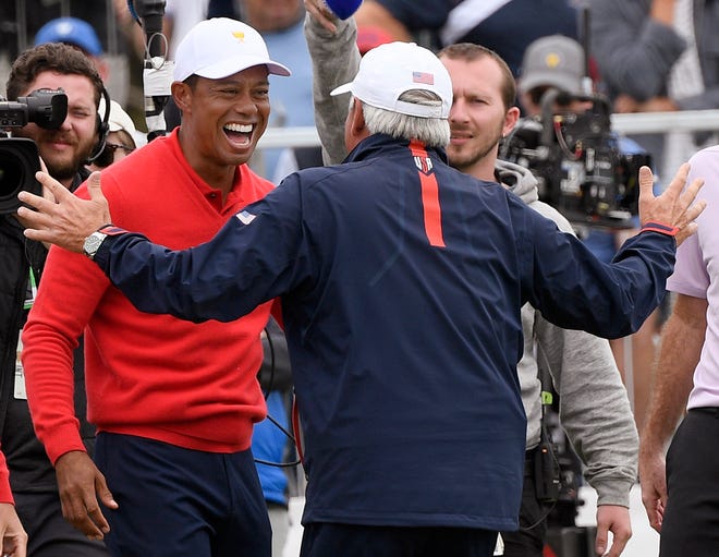 U.S. team player and captain Tiger Woods (left) celebrates with vice captain Fred Couples after Woods won his singles match during the President's Cup on Sunday at Royal Melbourne Golf Club in Melbourne. [AP Photo/Andy Brownbill]