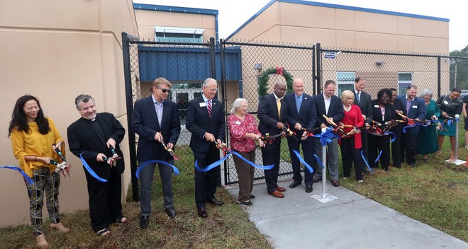 Wednesday was a day of celebration for all those who have endeavored for years to open the first large-scale homeless shelter in Volusia County. Among those pictured in front of First Step Shelter at Wednesday’s ribbon-cutting ceremony are First Step Shelter Board members, Daytona Beach city commissioners, County Council members, the Rev. Phil Egitto, Volusia County Judge Belle Schumann and Halifax Health official Bob Williams. [News-Journal/David Tucker]
