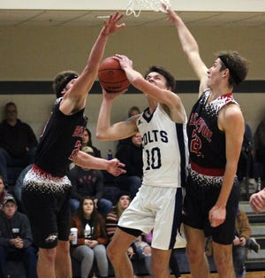 Hillsdale Academy's Lukas Tharp (10) threads the needle between Bellevue's Carson Betz (left) and Carter Wing (22) for a layup during Monday's game. (JAMES GENSTERBLUM/Hillsdale Daily News)