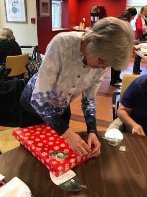 Youville Place resident Eleanor Morrissey helps wrap a gift as part of the "Be a Santa to a Senior" program. [Wicked Local Staff Photo / Ross Cristantiello]