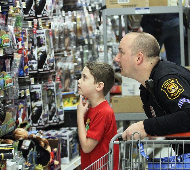 Hero JeffþÄàBingaman helps a youngster shop for a present at Walmart onþÄàSaturday morning as part of Shop With a Hero in Sturgis. [Brandon Watson Photo]