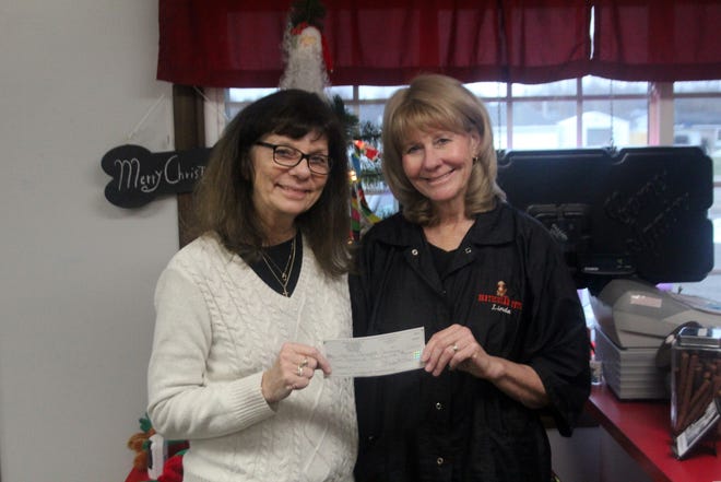 Ionia Community Awareness President Diane Grummet (left) and Particular Pets owner Linda McPherson pose for a photo with a check on Monday, Dec. 16, at Particular Pets, 2389 N. State Road, in Ionia. [EVAN SASIELA/SENTINEL STAFF]