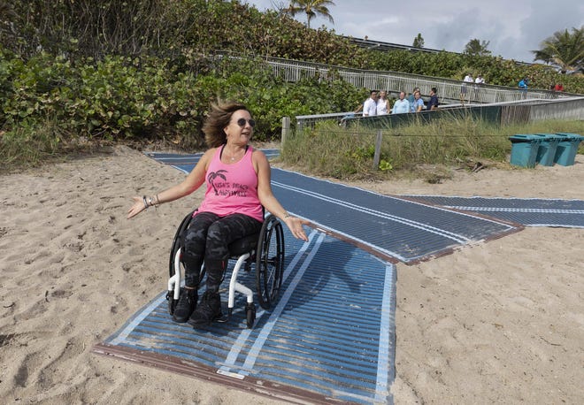 Lisa Lynch tries out the newly-installed Mobi-Mat at Oceanfront Park Beach on Dec. 12, 2019, in Boynton Beach. The mat allows independent beach access over the sand for people with disabilities, those who use wheelchairs, walkers or strollers, and the elderly. {GREG LOVETT / palmbeachpost.com}
