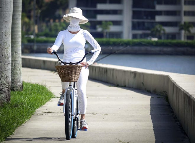 A bicyclist is well-protected from the sun's rays on June 26, 2019, while pedaling along South Flagler Drive in West Palm Beach. A heat advisory had been issued that day. The previous day's temperature was 95 degrees while the heat index reached 106. [BRUCE R. BENNETT/palmbeachpost.com]