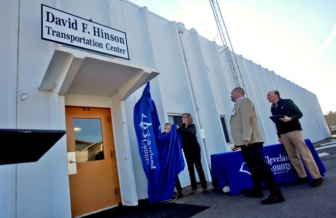 From right, Bill McCarter and David Pless watch as Annette McCarter and Christine Hinson, daughter and wife of the late David Hinson, unveil a sign at the newly named David F. Hinson Transportation Center on Thursday. [Brittany Randolph/The Star]