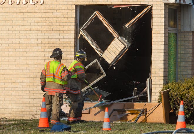 A Springfield firefighter pulls down the remains of a window frame broken by a vehicle that drove through the wall of the Korean United Presbyterian Church, 2501 East Sangamon Ave., Friday, Dec. 20, 2019. The vehicle crashed through the wall and came to a stop inside the building. [Ted Schurter/The State Journal-Register]
