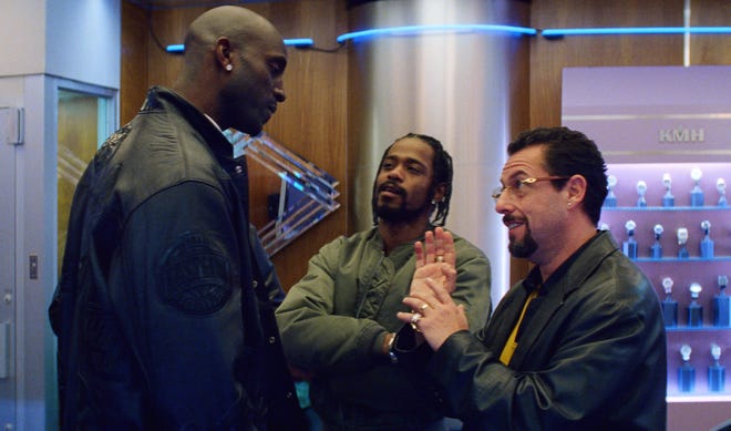 Kevin Garnett (left) and Adam Sandler make a deal over a gem and a ring while LaKeith Stanfield listens in. [A24]