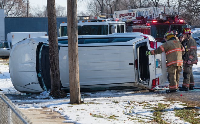 Springfield firefighters examine a Dodge Journey involved in a single-car accident that damaged at least two power poles on Melrose Street between 14th and 15th Streets Saturday, Dec. 21, 2019. Occupants of the vehicle had to be extricated through the front windshield. [Ted Schurter/The State Journal-Register]
