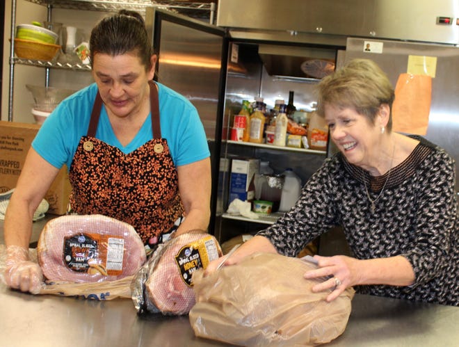 Susie LeFevre and Palmer Giron take inventory of hams that are brought in for the Christmas Eve lunch at the St. Anthony Catholic Church. [NANCY HASTINGS PHOTO]