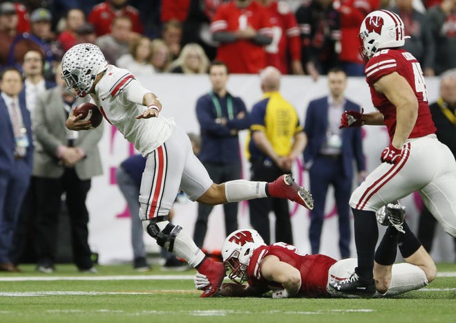 Ohio State quarterback Justin Fields, getting tripped up by Wisconsin linebacker Jack Sanborn in the Big Ten championship game on Dec. 7, hopes to wear a smaller knee brace against Clemson in a College Football Playoff semifinal. [Adam Cairns/Dispatch]