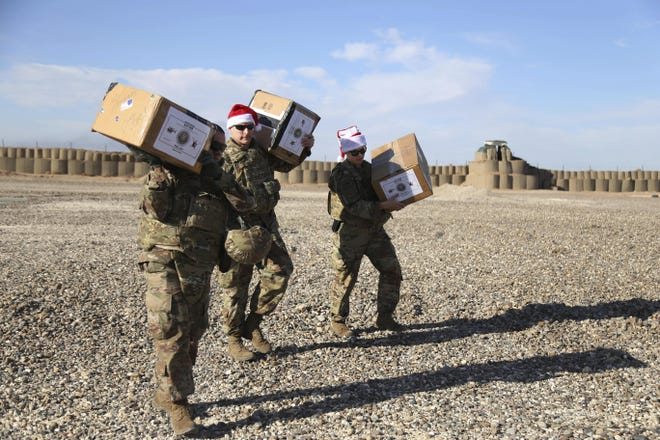 In this Monday, Dec. 23, 2019, photo, U.S. soldiers deliver Christmas gifts to their comrades on a base near the al-Omar oilfield in eastern Syria. It's an operation is called Holiday Express - in addition to delivering presents, the U.S.-led coalition forces brought a U.S. military band to play Christmas carols and music to several bases in eastern Syria. (AP Photo/Farid Abdul-Wahid)