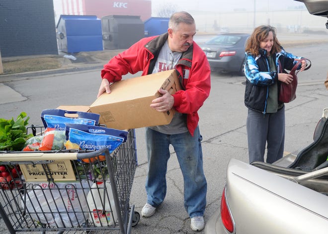 River Valley Regional Food Bank volunteer Rich Isham, left, loads a cart of food for Joelena Schmidt at the food bank on Monday, Dec. 23, 2019. The River Valley Regional Food Bank and the Crawford-Sebastian Community Development Council hosted a community commodities holiday giveaway at the facility, 1617 South Zero Street in Fort Smith. [BRIAN D. SANDERFORD/TIMES RECORD]