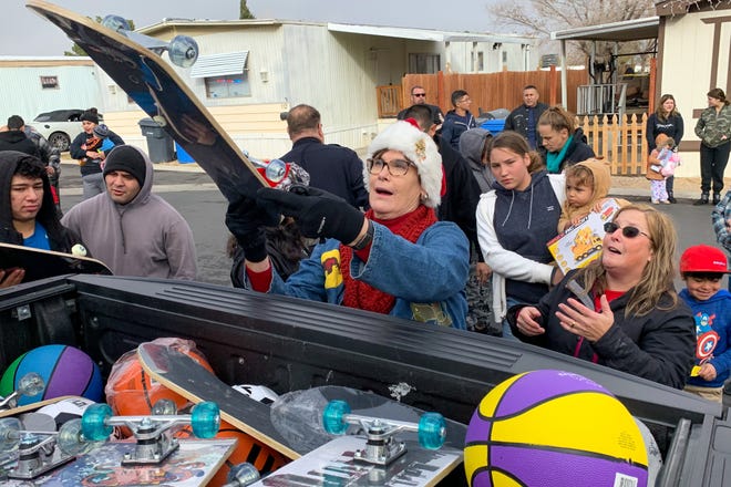 Barstow Mayor Julie Hackbarth-McIntyre, center, delivers a skateboard to one lucky child Tuesday morning as part of the Barstow Police Department’s Police Activities League’s 24th annual Christmas Cops and Kids Program. [JOSE QUINTERO/DAILY PRESS]